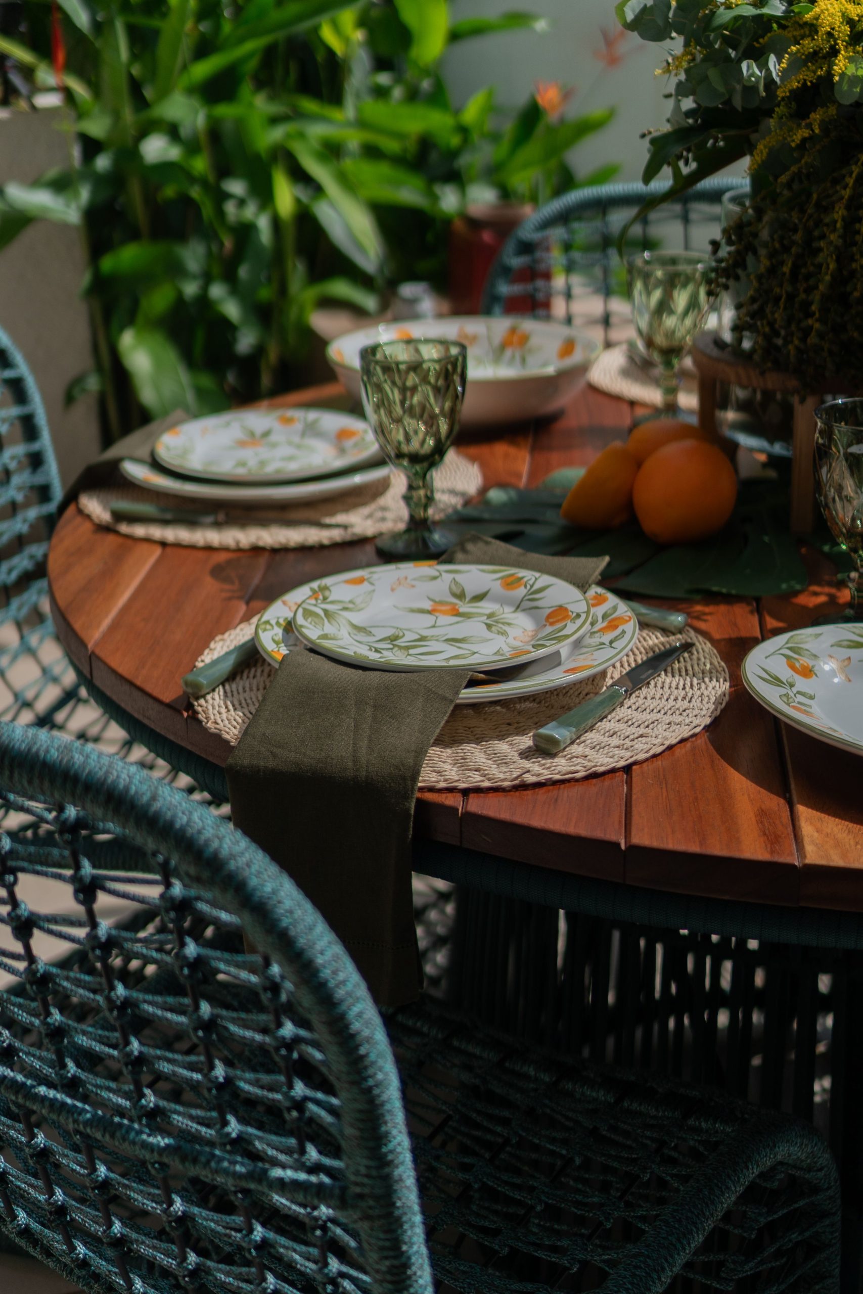 Charming outdoor table adorned with floral plates, glassware, and lush greenery, perfect for a cozy gathering.