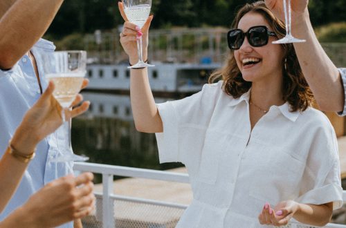 Group of friends enjoying a joyful toast with wine glasses on a sunny day.