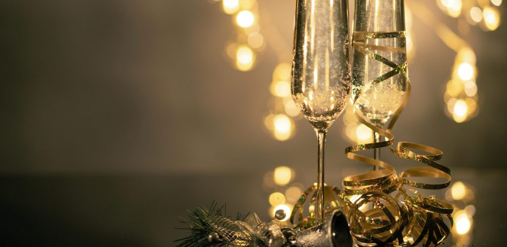 Champagne glasses with ribbons against festive bokeh lights.